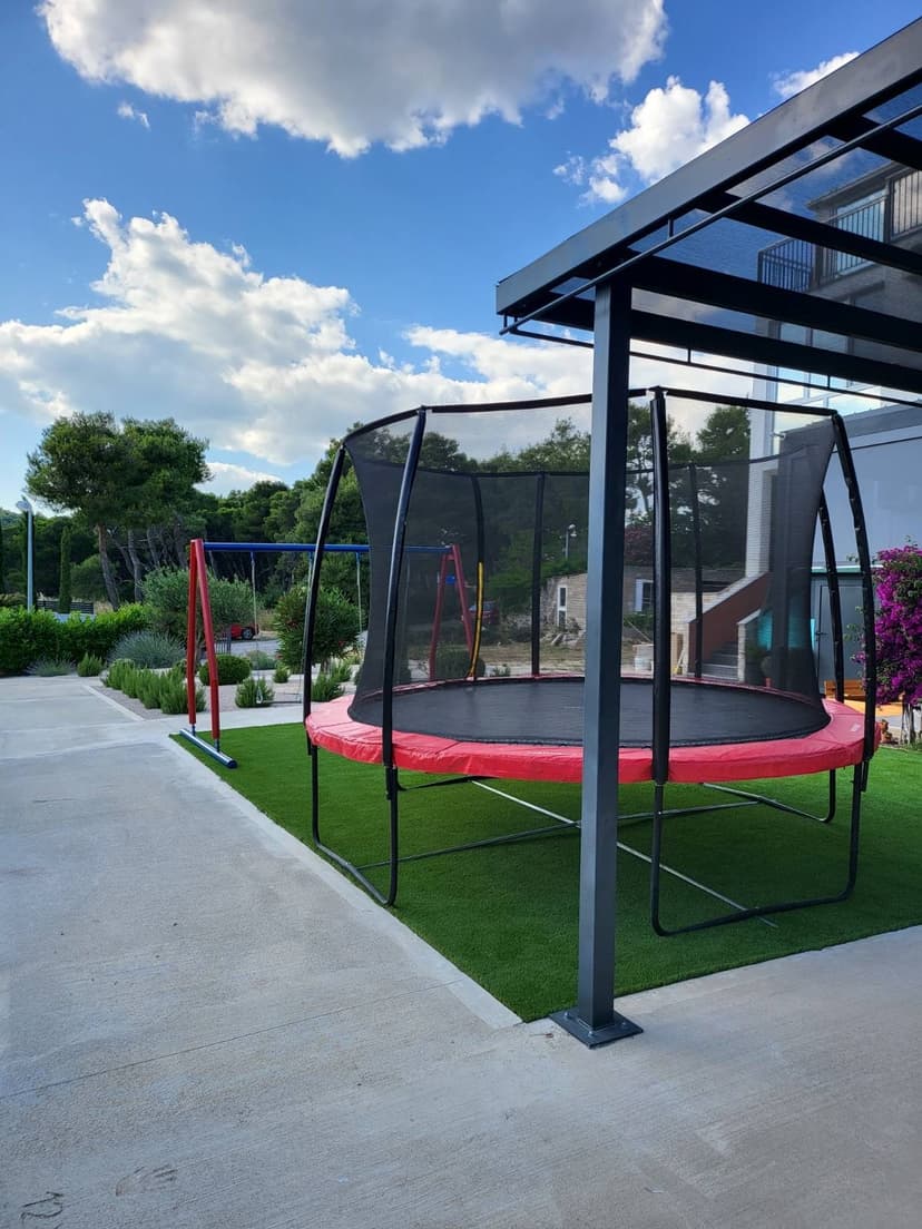 Pohled na zahradu s trampolínou a houpačkou
