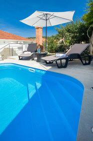 Soukromý bazén pro hosty s lehátky a slunečníkem